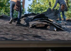 A residential roof with exposed wooden decking, showing plywood panels before new shingles are installed.